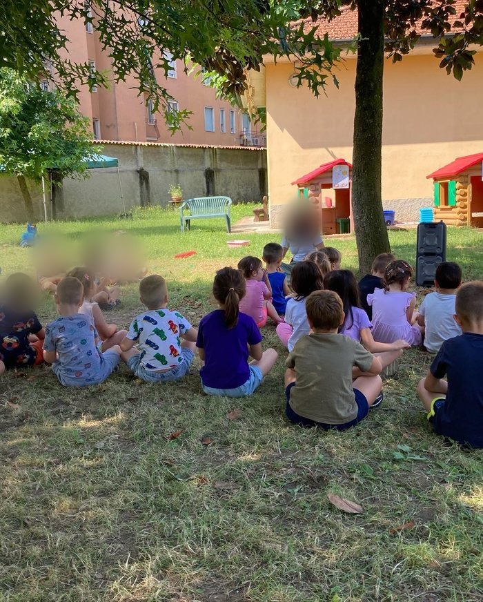 Bambini seduti in cerchio sul prato con un'insegnante
