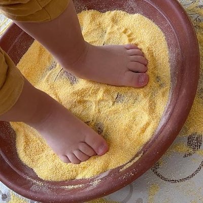 Piedini di un bambino nella farina gialla